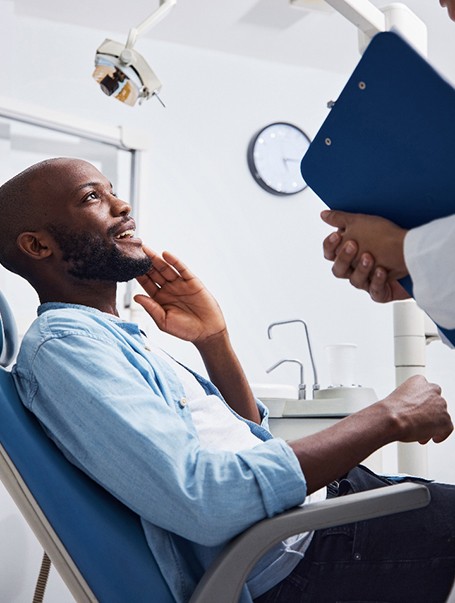 Younger man talking to dentist about the cost of a dental crown in Bozeman