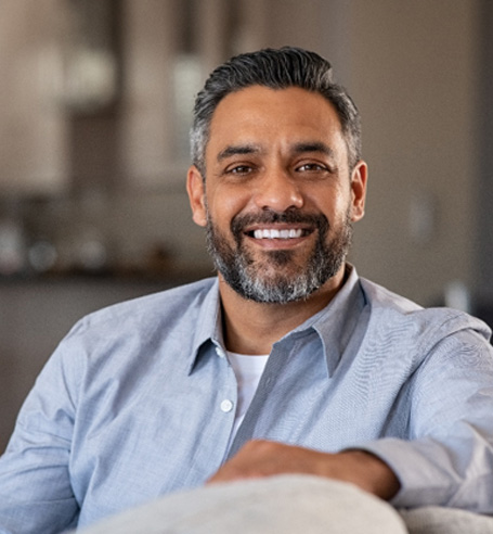 Bearded man sitting on couch and smiling