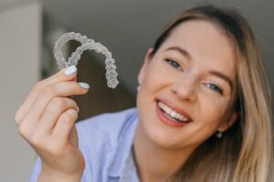 Woman holding up 2 clear aligners.